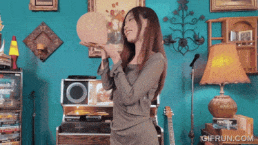 a woman holding a sphere in her hands with a gifrun.com logo on the bottom right