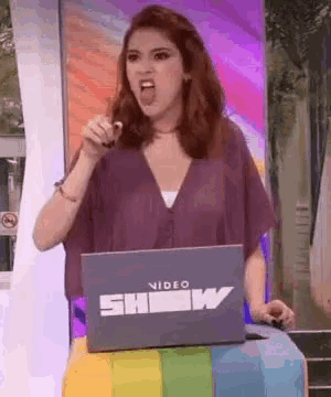 a woman is standing in front of a laptop that says show