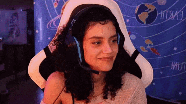 a woman wearing headphones is smiling in front of a wall with the word hitrako written on it