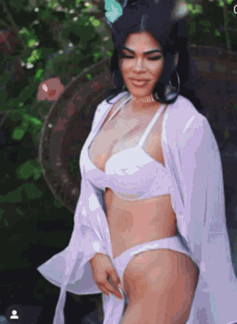 a woman in a white bikini and a white robe is posing for a photo .