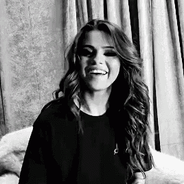 a black and white photo of a woman with long hair laughing .