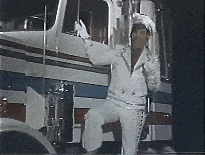 a man in a white suit is standing in front of a large truck