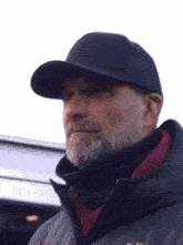 a man with a beard wearing a hat and a jacket .