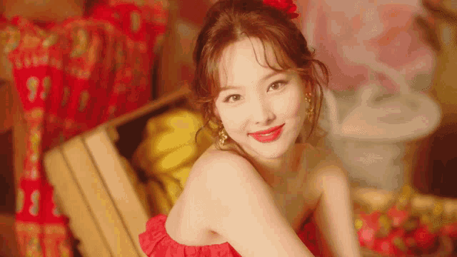 a woman in a red dress is sitting on a wooden bench and smiling .