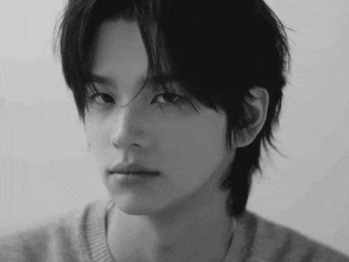 a black and white photo of a young man with a sweater on