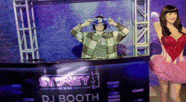 a man wearing headphones stands in front of a dj booth that says sydney on it