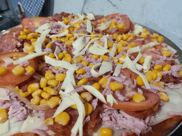 a pizza with corn tomatoes and cheese on it