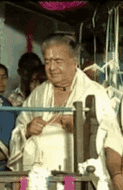 a man in a white robe sits in a chair