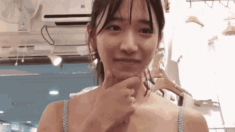 a woman in a blue bra holds her hand to her chin and looks at the camera .