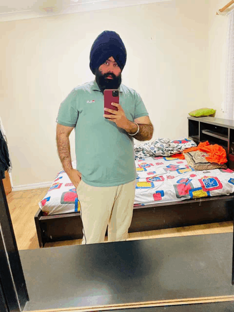 a man in a turban takes a selfie in front of a bedroom mirror