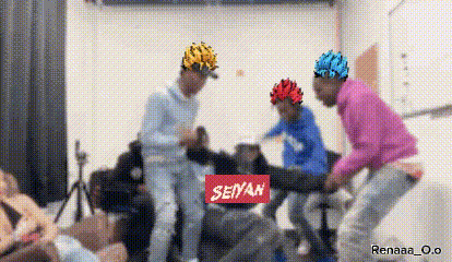 a group of people are playing a video game in a room with a sign that says seiyah on it .
