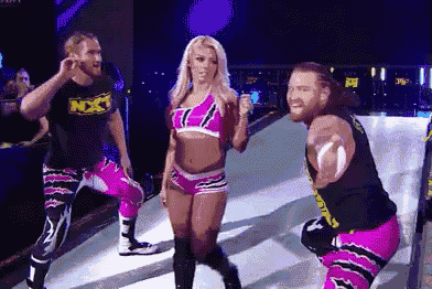 a group of wrestlers are standing on a stage and one of them is wearing a shirt that says nxt .