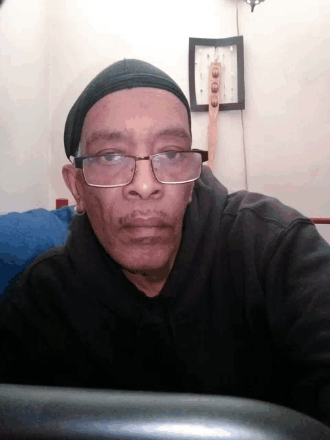 a man wearing glasses and a beanie looks at the camera