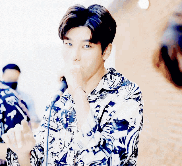 a young man singing into a microphone wearing a shirt that says ' i love you ' on it