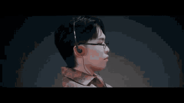 a man wearing glasses and ear buds is looking at something .