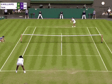 a tennis player stands on a court with a scoreboard that says s.williams tan
