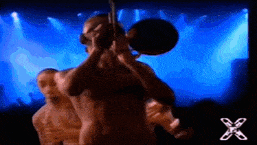 a man without a shirt is playing a trumpet on stage .