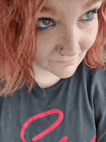 a woman with red hair and a nose ring is wearing a black shirt with the number 0 on it