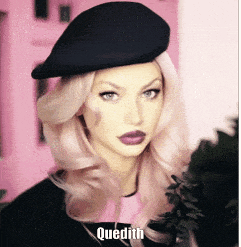a woman with pink hair wearing a black hat with quedith written on it