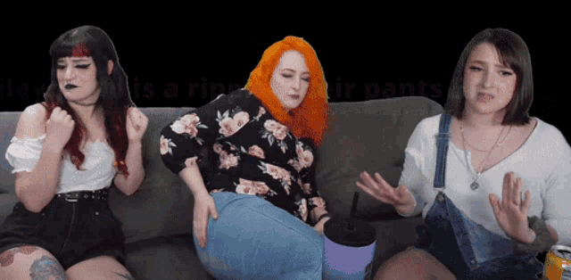 three women are sitting on a couch and one of them is wearing a floral shirt
