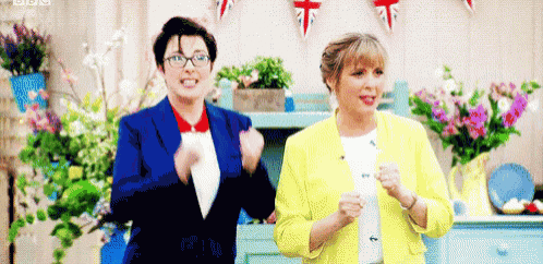 two women are standing next to each other in a room with flowers in vases .