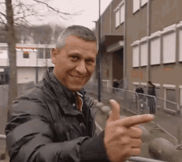 a man in a black jacket is giving a thumbs up sign