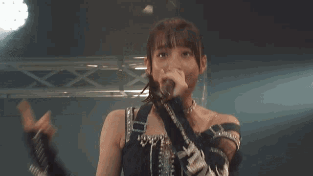 a girl in a black dress is smiling on stage
