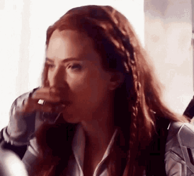 black widow is drinking a glass of wine while sitting at a table .