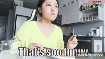 a woman in a yellow sweater is sitting at a table with a plate of food and says that 's soo funny