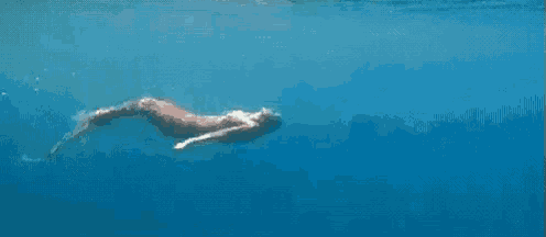 a mermaid is swimming in the ocean near a rock