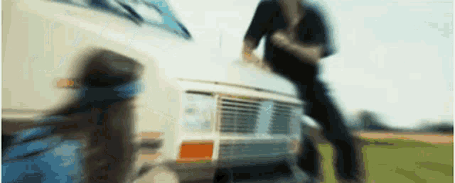 a blurry picture of two people standing next to a white van .