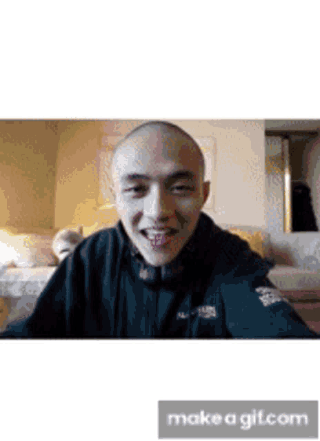 a man with a shaved head is smiling while wearing a north face jacket