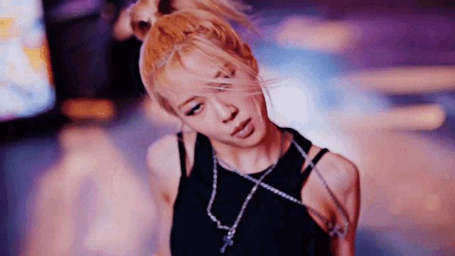 a close up of a woman wearing a black tank top and a necklace