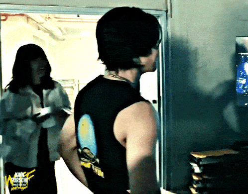 a man in a black tank top is standing in a doorway next to a woman