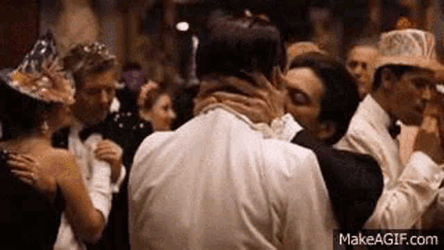 a couple of men are kissing in a crowd of people .
