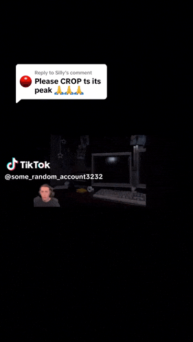 a man is sitting at a desk with two computer monitors and a keyboard in a dark room .