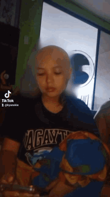 a young boy with a bald head wearing a shirt that says agayt