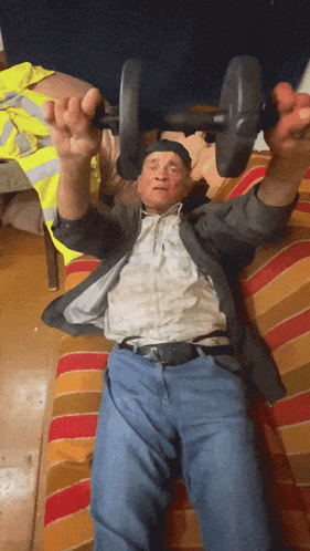 an elderly man is lifting a dumbbell on a couch
