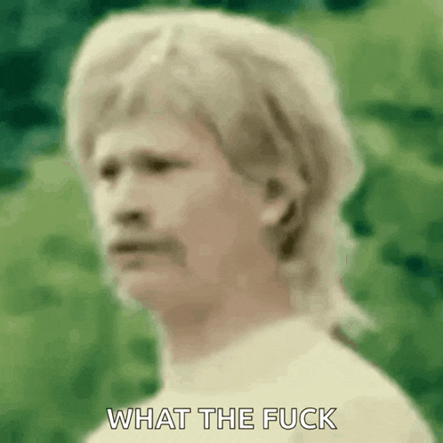 a man with blonde hair and a mustache is standing in front of a green background .