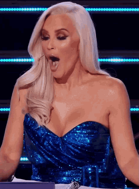 a woman in a blue sequined strapless dress with her mouth open