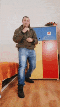 a man is dancing in front of a colorful closet in a room .