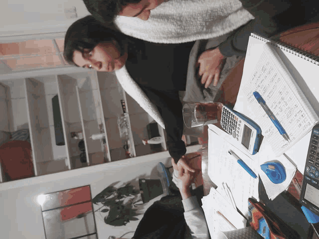 a man and a woman sit at a table with a calculator and a notebook with numbers on it