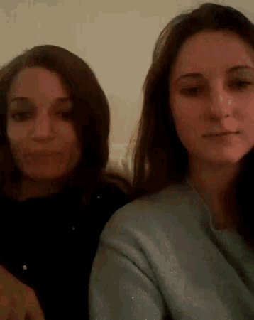 two women are sitting next to each other and one is wearing a sweater