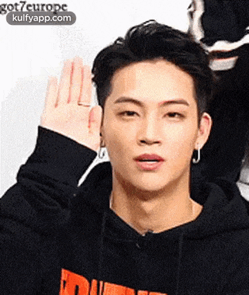 a young man wearing a black hoodie is waving his hand in the air .