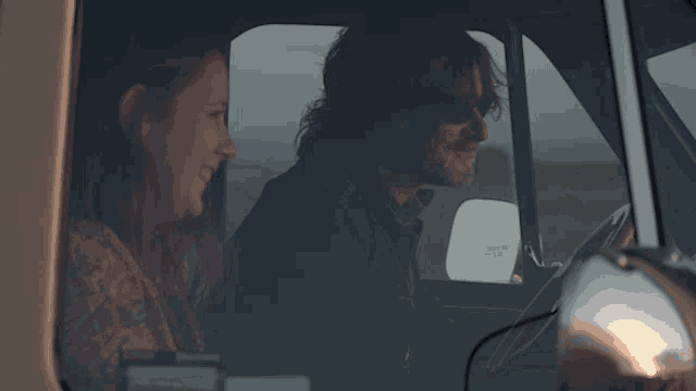 a man and a woman are sitting in a car and the man is wearing sunglasses and the woman is wearing sunglasses