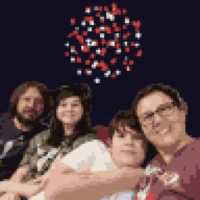 a group of people are posing for a picture with fireworks in the background