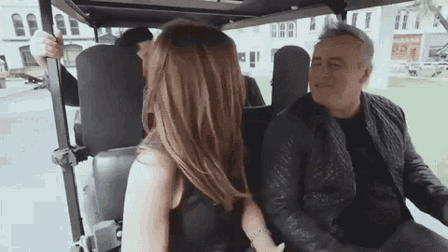 a man and woman are sitting in a golf cart .