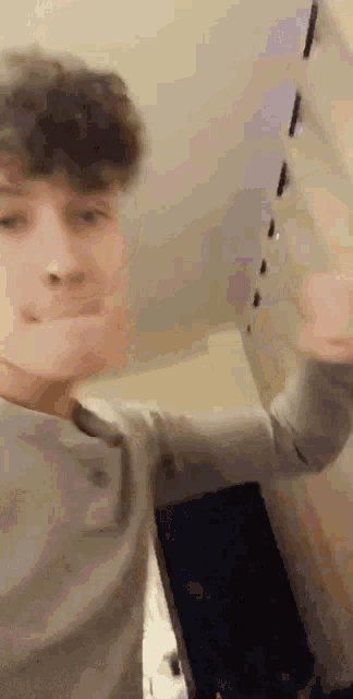 a young man is making a funny face while standing in front of a wall .
