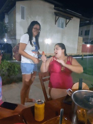 two women are sitting at a table with a can of beer on the table