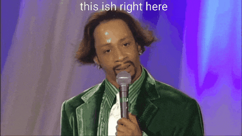 a man in a green jacket is standing on a stage with a microphone and the words this ish right here above him